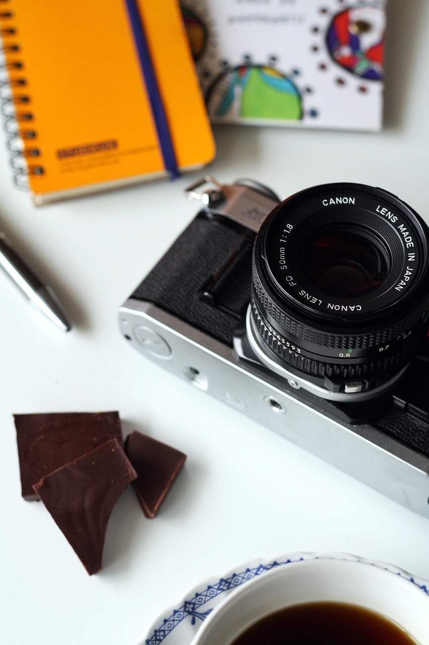 A vintage camera and notebook styled on a white surface